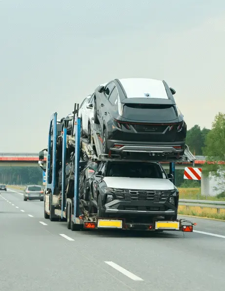 Car carrier truck transporting multiple SUVs on a highway during daytime.