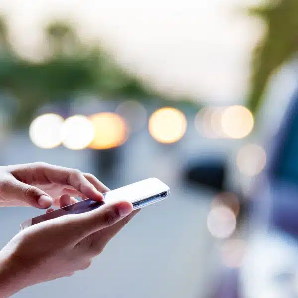 Person using smartphone to contact a cash for cars service and sell a used car online